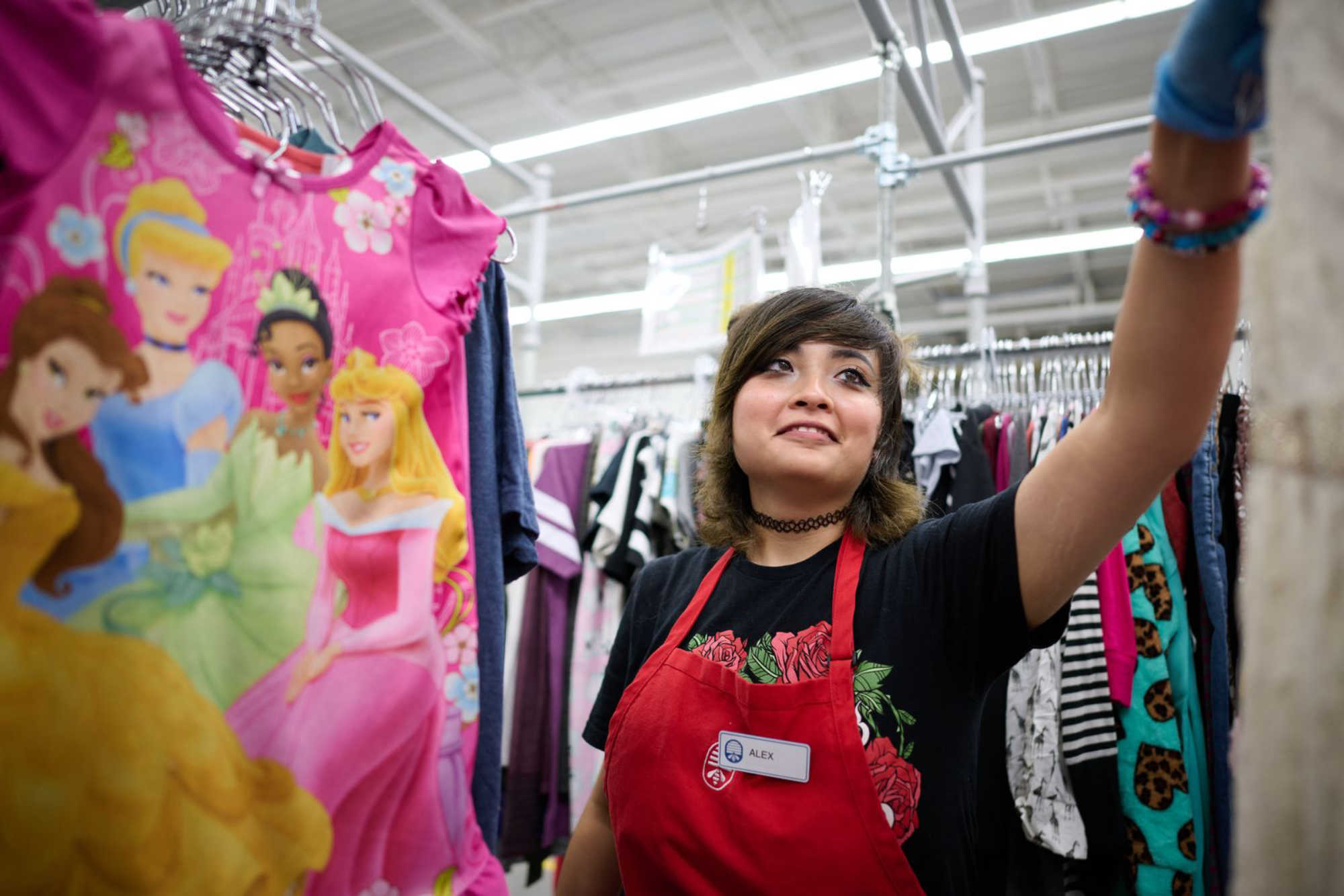 Thrift store worker puts clothes on hangers